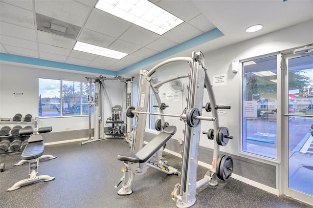 exercise room with a drop ceiling and baseboards