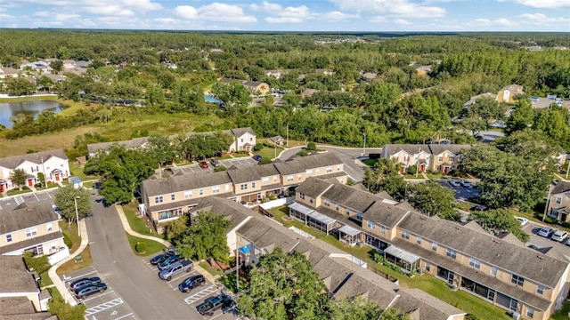 aerial view of residential area featuring a heavily wooded area and a large body of water