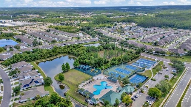aerial view of property's location with a pool, a nearby body of water, and nearby suburban area