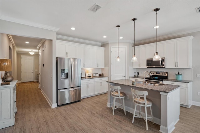 764 W Bayshore Dr, Tarpon Springs, FL 34689 - kitchen with stainless steel appliances, light wood finished floors, a kitchen island with sink, backsplash, and baseboards