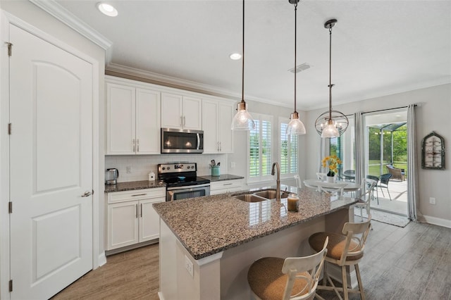 764 W Bayshore Dr, Tarpon Springs, FL 34689 - kitchen with appliances with stainless steel finishes, a sink, light wood-type flooring, an island with sink, and ornamental molding