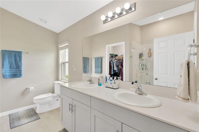 full bathroom featuring a stall shower, toilet, a walk in closet, double vanity, and baseboards