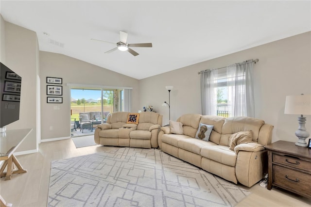 living room with ceiling fan, plenty of natural light, vaulted ceiling, light wood-style flooring, and baseboards