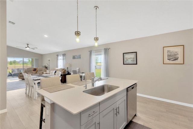 kitchen featuring a sink, open floor plan, stainless steel dishwasher, hanging light fixtures, and light countertops