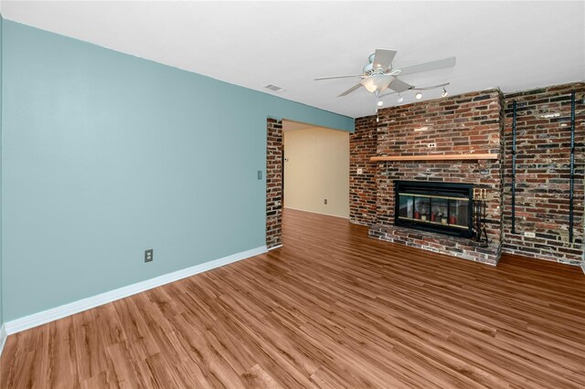 6536 115th Ln, Seminole, FL 33772 - unfurnished living room featuring a ceiling fan, wood finished floors, a fireplace, baseboards, and brick wall