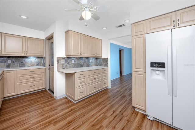 6536 115th Ln, Seminole, FL 33772 - kitchen featuring white fridge with ice dispenser, light countertops, light brown cabinetry, light wood-style floors, and tasteful backsplash