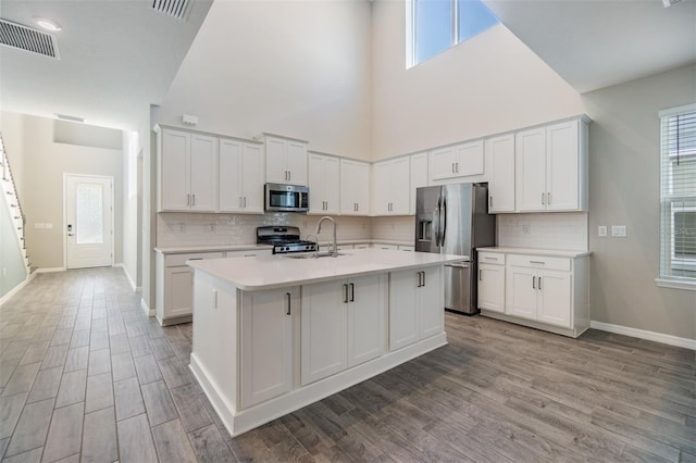 13614 Stevenson Ln, Odessa, FL 33556 - kitchen featuring appliances with stainless steel finishes, a sink, a high ceiling, light countertops, and a center island with sink