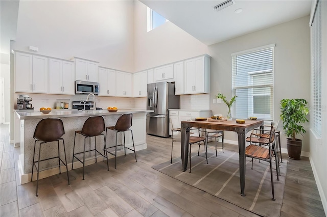 13614 Stevenson Ln, Odessa, FL 33556 - kitchen with appliances with stainless steel finishes, a high ceiling, backsplash, light countertops, and an island with sink