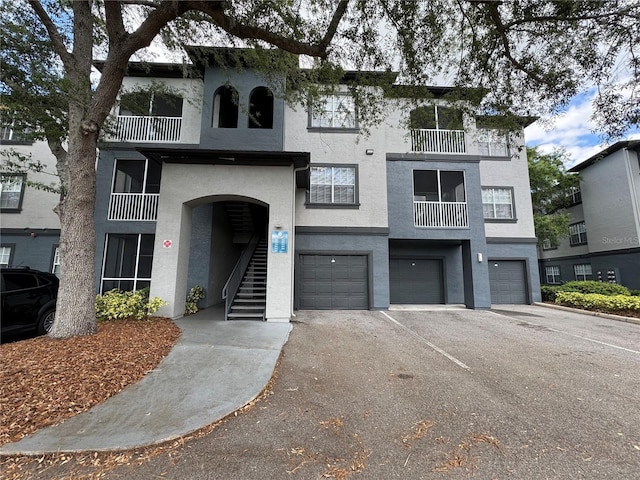 13243 Sanctuary Cove Dr Unit 204, Temple Terrace, FL 33637 - view of property featuring a garage, stucco siding, driveway, and stairway