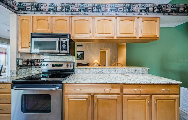 699 Merlins Ct, Tarpon Springs, FL 34689 - kitchen featuring appliances with stainless steel finishes, light stone countertops, light brown cabinets, and a peninsula