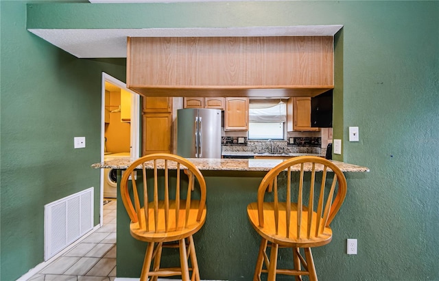 699 Merlins Ct, Tarpon Springs, FL 34689 - kitchen featuring freestanding refrigerator, a sink, light tile patterned floors, decorative backsplash, and a breakfast bar