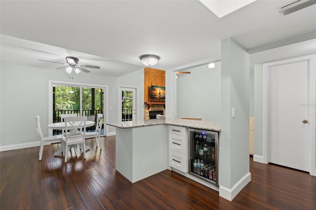2033 Arbor Dr, Clearwater, FL 33760 - kitchen with beverage cooler, dark wood-style flooring, baseboards, and light stone counters