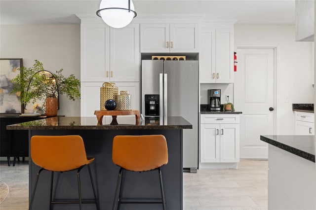kitchen featuring stainless steel refrigerator with ice dispenser, white cabinets, a breakfast bar area, and a center island