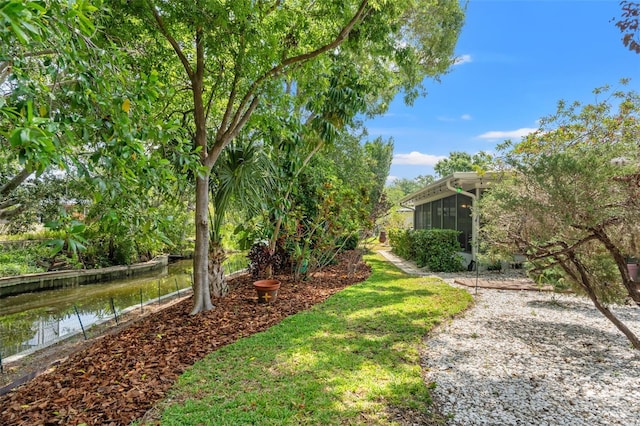 view of yard featuring a sunroom and a water view
