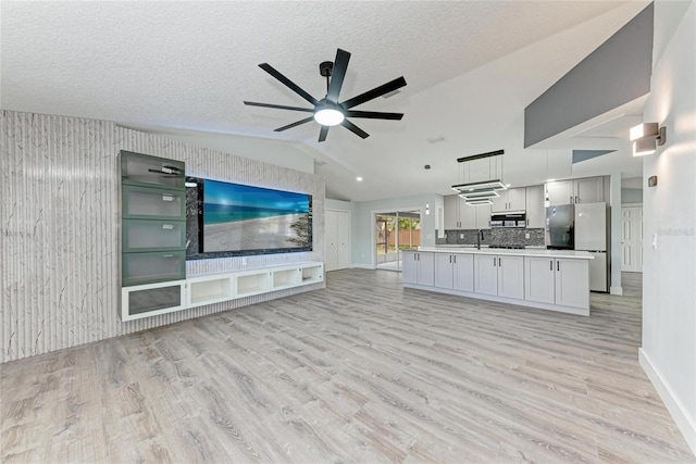3330 46th Ter E, Bradenton, FL 34203 - unfurnished living room with vaulted ceiling, a ceiling fan, light wood-style flooring, a sink, and baseboards
