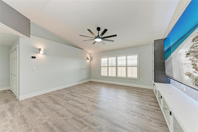 3330 46th Ter E, Bradenton, FL 34203 - unfurnished living room with a ceiling fan, lofted ceiling, light wood-style flooring, baseboards, and a textured ceiling