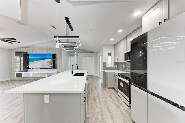 3330 46th Ter E, Bradenton, FL 34203 - kitchen with range with electric cooktop, light wood finished floors, gray cabinets, a center island with sink, and vaulted ceiling