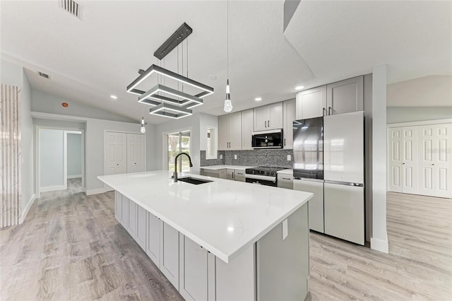 3330 46th Ter E, Bradenton, FL 34203 - kitchen with appliances with stainless steel finishes, a sink, lofted ceiling, gray cabinetry, and light wood finished floors