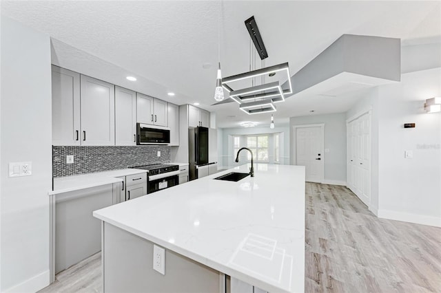 3330 46th Ter E, Bradenton, FL 34203 - kitchen featuring a sink, electric range, freestanding refrigerator, light wood-style floors, and a center island with sink