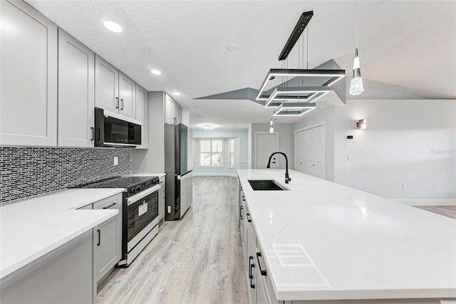3330 46th Ter E, Bradenton, FL 34203 - kitchen featuring a sink, a large island with sink, electric range, light wood-type flooring, and freestanding refrigerator