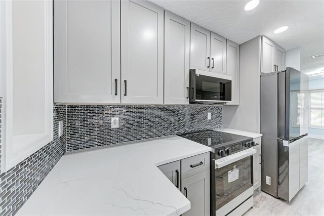 3330 46th Ter E, Bradenton, FL 34203 - kitchen featuring freestanding refrigerator, electric stove, decorative backsplash, light stone countertops, and recessed lighting