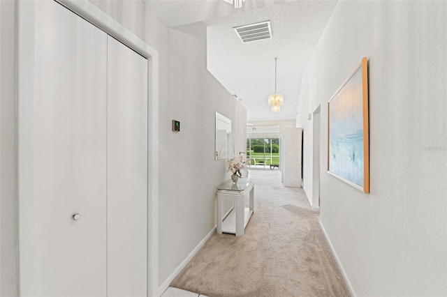9188 Rhett Ln, Weeki Wachee, FL 34613 - corridor featuring baseboards, light carpet, a textured ceiling, and a chandelier