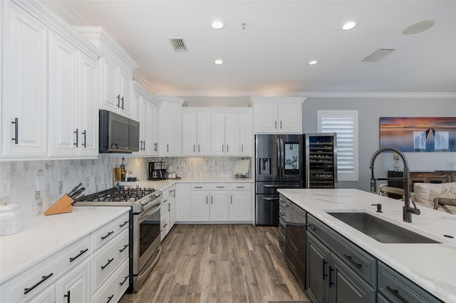 2750 Reserve Ct Unit 101, Dunedin, FL 34698 - kitchen featuring appliances with stainless steel finishes, a sink, white cabinetry, ornamental molding, and recessed lighting