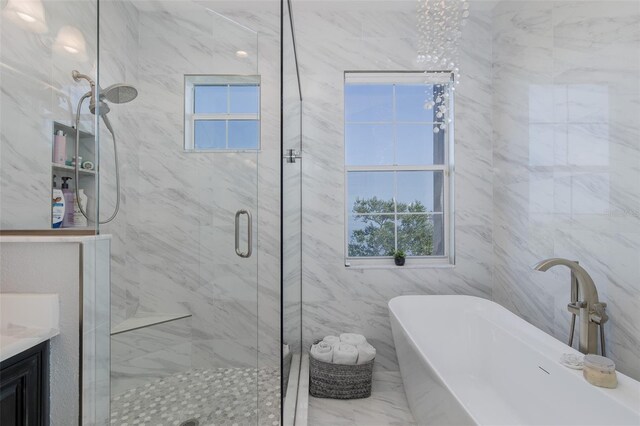 2750 Reserve Ct Unit 101, Dunedin, FL 34698 - full bathroom with a shower stall, healthy amount of natural light, a soaking tub, marble look tiles, and tile walls