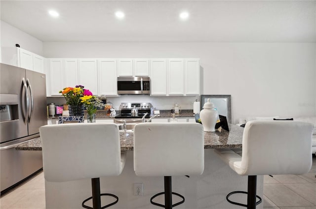 32965 Kaloko Rd, Wesley Chapel, FL 33543 - kitchen with appliances with stainless steel finishes, a kitchen breakfast bar, light tile patterned floors, white cabinets, and recessed lighting