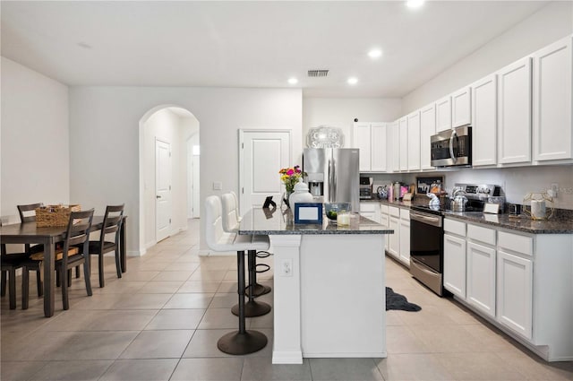 32965 Kaloko Rd, Wesley Chapel, FL 33543 - kitchen featuring stainless steel appliances, arched walkways, a breakfast bar area, recessed lighting, and a kitchen island