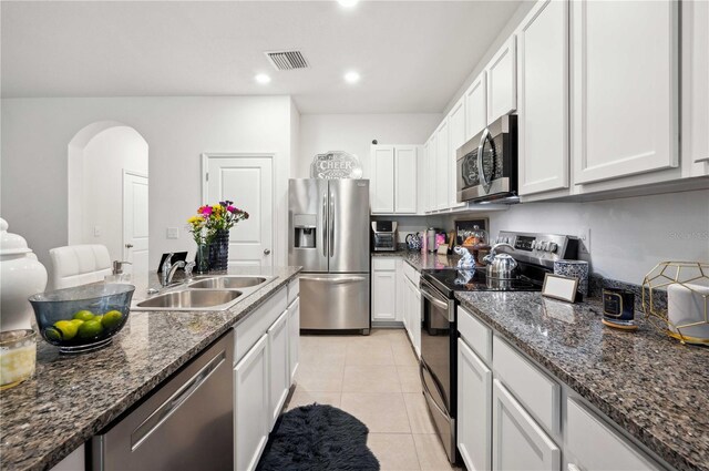 32965 Kaloko Rd, Wesley Chapel, FL 33543 - kitchen featuring stainless steel appliances, a sink, arched walkways, white cabinets, and light tile patterned floors