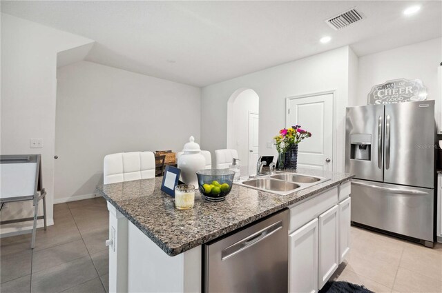 32965 Kaloko Rd, Wesley Chapel, FL 33543 - kitchen featuring stainless steel appliances, a sink, arched walkways, white cabinets, and light tile patterned floors