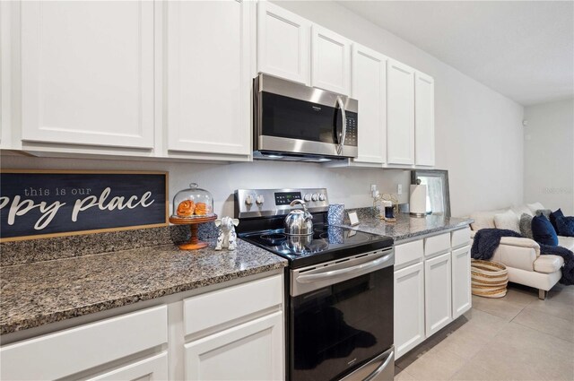 32965 Kaloko Rd, Wesley Chapel, FL 33543 - kitchen with stainless steel appliances, white cabinets, stone countertops, light tile patterned flooring, and open floor plan