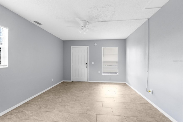 unfurnished room featuring ceiling fan, baseboards, and a textured ceiling