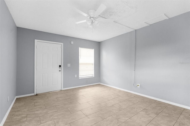 unfurnished room featuring a ceiling fan, a textured ceiling, and baseboards