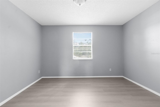 unfurnished room with wood finished floors, baseboards, and a textured ceiling