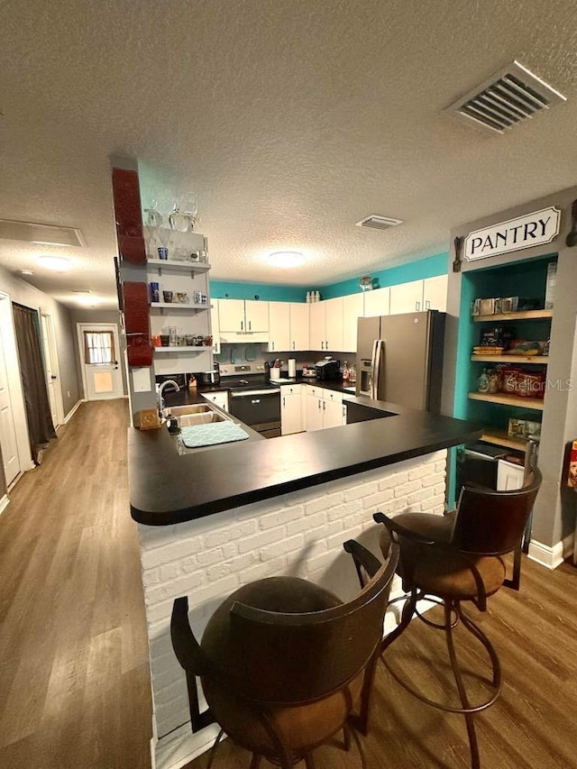 10411 Summerview Cir, Riverview, FL 33578 - kitchen featuring stainless steel fridge, dark countertops, wood finished floors, a textured ceiling, and white cabinets