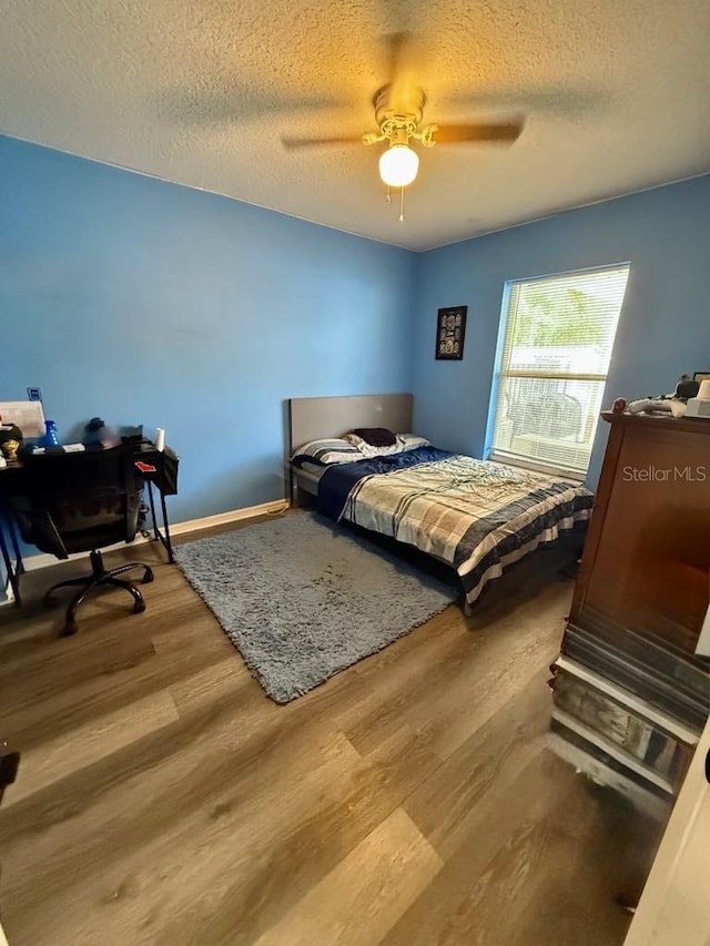 10411 Summerview Cir, Riverview, FL 33578 - bedroom with wood finished floors, a textured ceiling, a ceiling fan, baseboards, and a desk