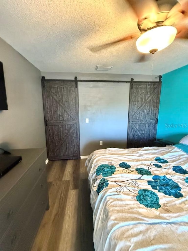 10411 Summerview Cir, Riverview, FL 33578 - bedroom featuring a barn door, wood finished floors, a textured ceiling, and ceiling fan