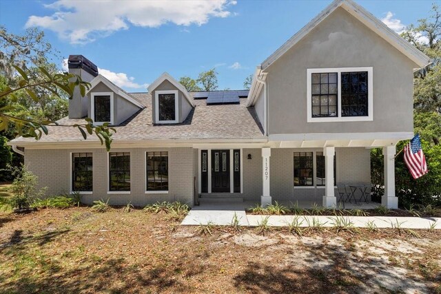 11207 Donneymoor Dr, Riverview, FL 33569 - view of front of house with solar panels, brick siding, a chimney, and a shingled roof