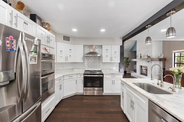 11207 Donneymoor Dr, Riverview, FL 33569 - kitchen featuring appliances with stainless steel finishes, wall chimney range hood, a sink, tasteful backsplash, and dark wood-type flooring