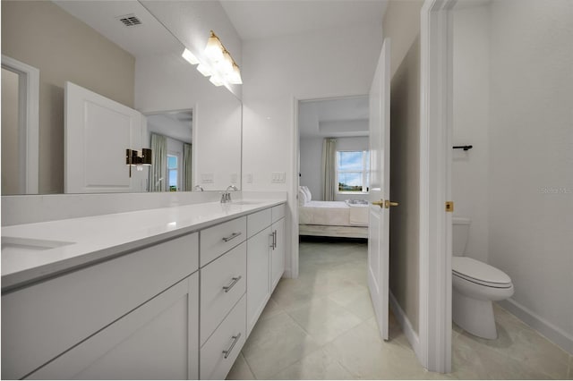 8589 Saint Kitts Cir, Englewood, FL 34224 - ensuite bathroom featuring double vanity, toilet, tile patterned flooring, and baseboards