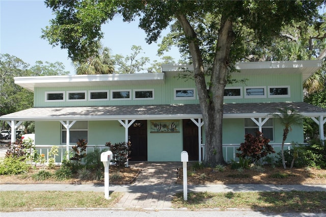 mid-century inspired home with covered porch and a shingled roof