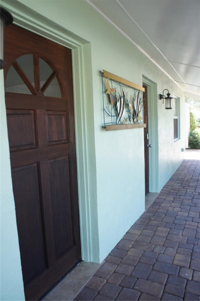entrance to property with a porch and stucco siding