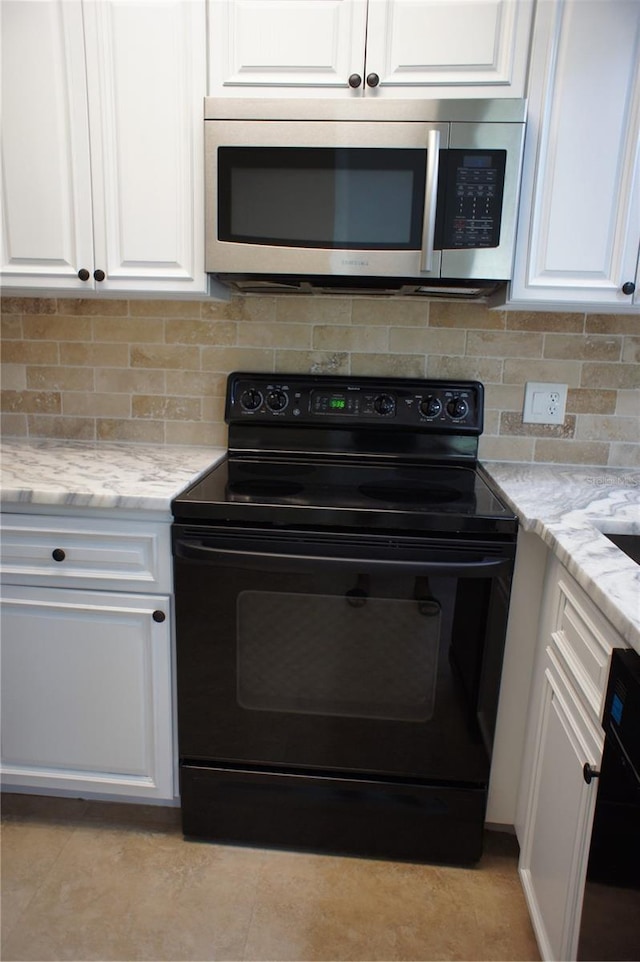 kitchen featuring black / electric stove, stainless steel microwave, white cabinetry, decorative backsplash, and light stone countertops