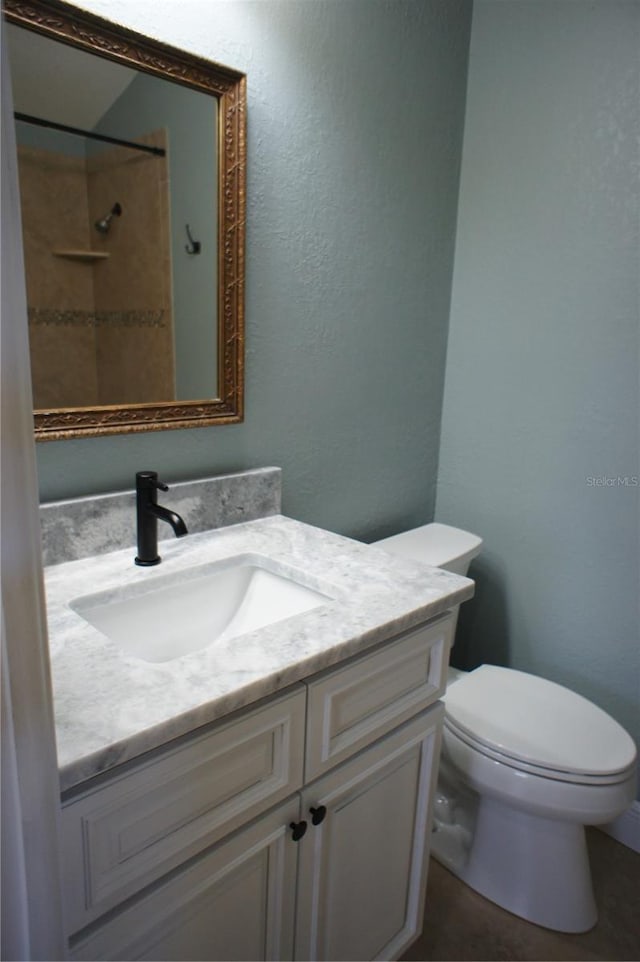 bathroom with vanity, toilet, and a textured wall