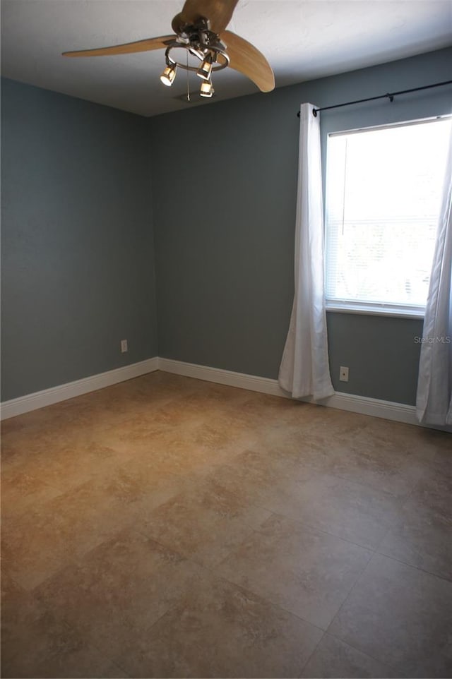 unfurnished room with ceiling fan and baseboards