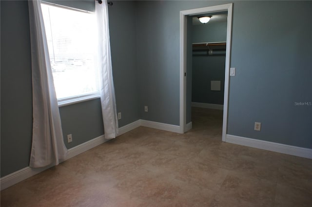 unfurnished bedroom featuring a walk in closet, a closet, and baseboards