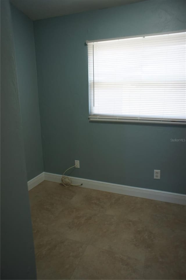 unfurnished room with baseboards