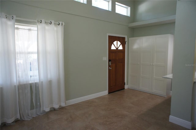 entryway featuring a towering ceiling and baseboards
